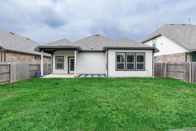 back of property with a lawn, a fenced backyard, a patio area, and a shingled roof