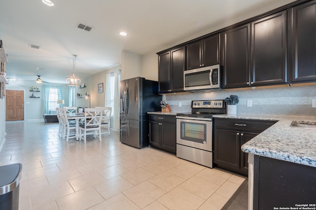 kitchen with stainless steel appliances, light stone countertops, visible vents, and decorative backsplash