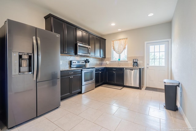kitchen featuring light stone counters, decorative backsplash, a sink, and stainless steel appliances