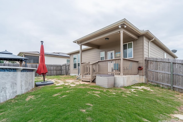 back of property with a yard, a deck, a gazebo, and a fenced backyard