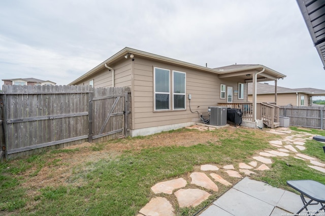 back of property featuring a lawn, a fenced backyard, a deck, and central AC unit