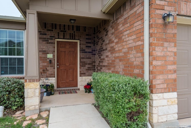 doorway to property featuring board and batten siding and brick siding