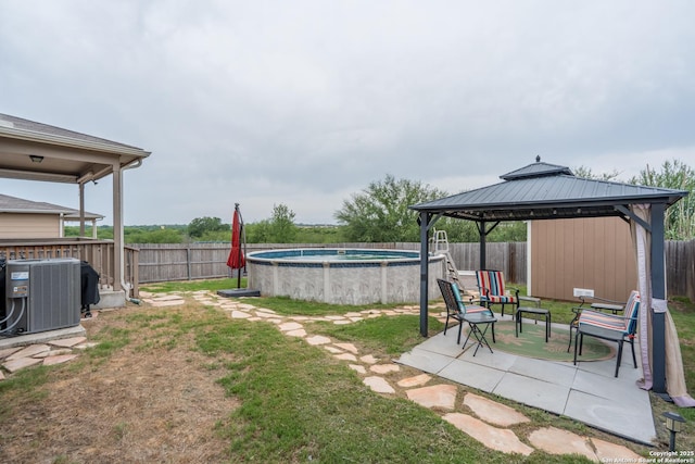 view of yard with a gazebo, a fenced backyard, a fenced in pool, central AC unit, and a patio