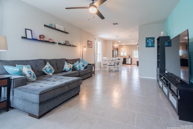living area with light tile patterned floors, baseboards, ceiling fan, and visible vents