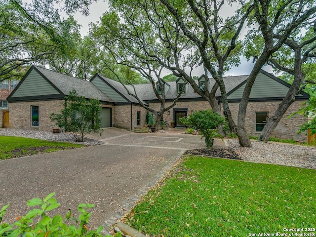 view of front facade featuring a garage, concrete driveway, a front lawn, and brick siding