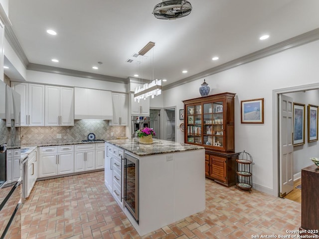 kitchen featuring beverage cooler, ornamental molding, stainless steel oven, and brick floor