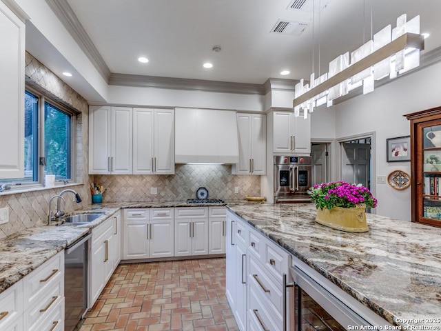 kitchen with a sink, appliances with stainless steel finishes, brick floor, and backsplash