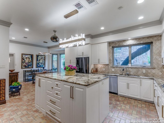 kitchen featuring freestanding refrigerator, visible vents, brick floor, and a center island