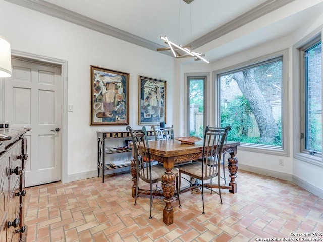 dining room featuring crown molding, baseboards, plenty of natural light, and brick floor