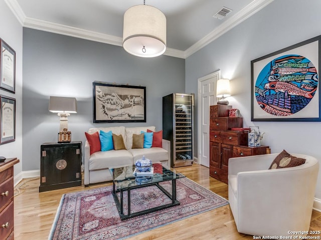 living area featuring crown molding, visible vents, wood finished floors, baseboards, and beverage cooler