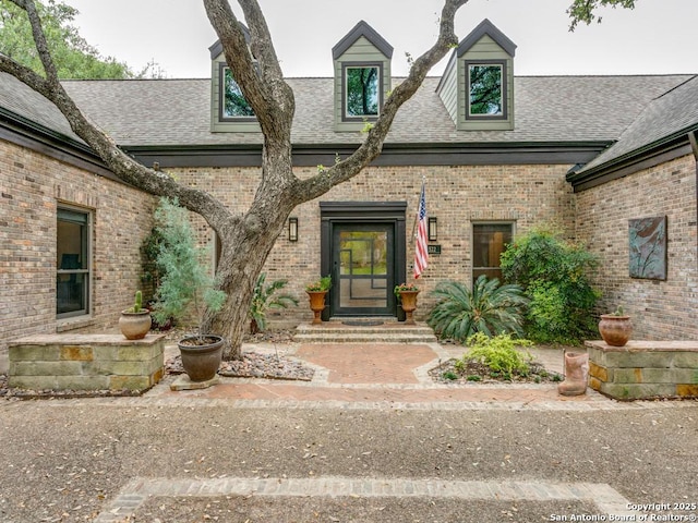 property entrance featuring brick siding and roof with shingles
