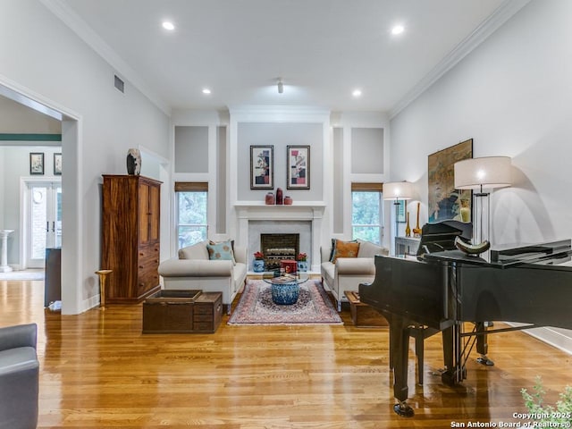 living room featuring ornamental molding, a wealth of natural light, light wood-style flooring, and a fireplace