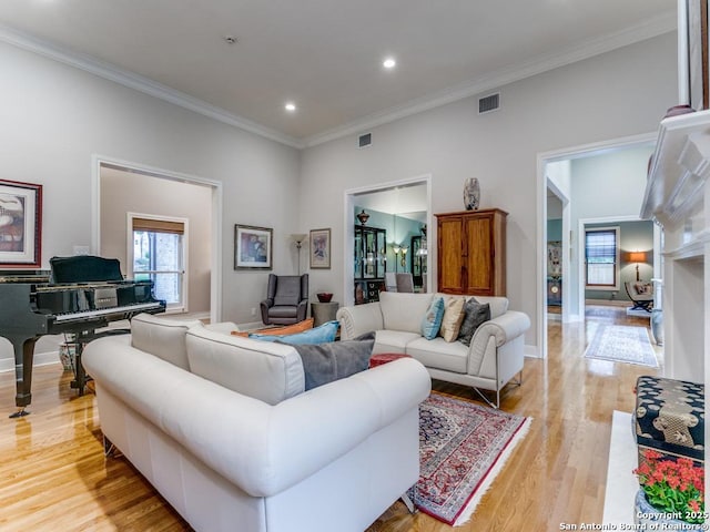 living area featuring visible vents, baseboards, light wood finished floors, ornamental molding, and recessed lighting
