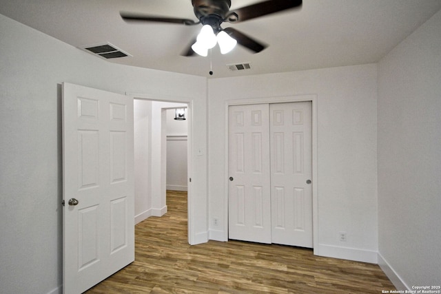 unfurnished bedroom with baseboards, wood finished floors, and visible vents