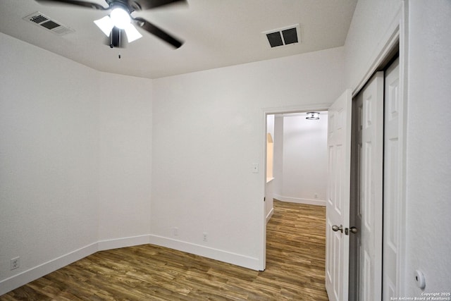 unfurnished bedroom with ceiling fan, baseboards, visible vents, and wood finished floors