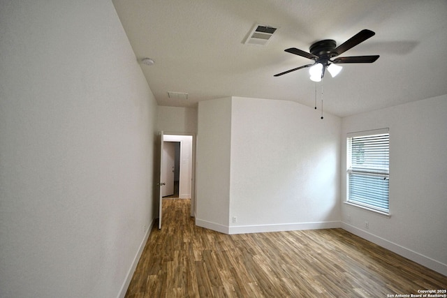 unfurnished room with visible vents, wood finished floors, baseboards, a ceiling fan, and vaulted ceiling