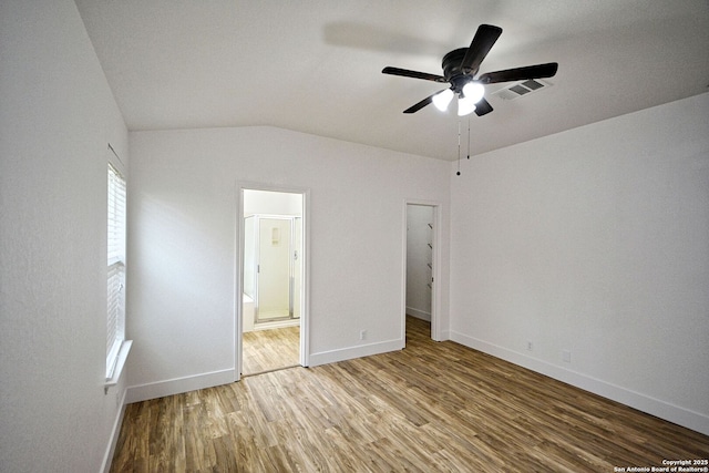 unfurnished bedroom with connected bathroom, baseboards, visible vents, and wood finished floors
