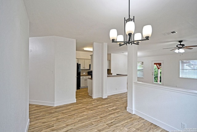 empty room with baseboards, ceiling fan with notable chandelier, light wood-style flooring, and visible vents