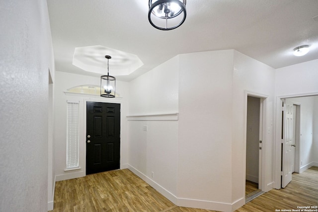 foyer featuring baseboards, wood finished floors, and a raised ceiling