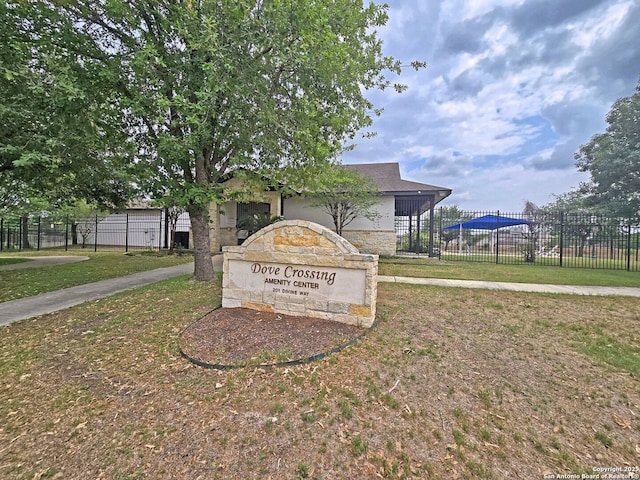 community / neighborhood sign featuring a yard and fence