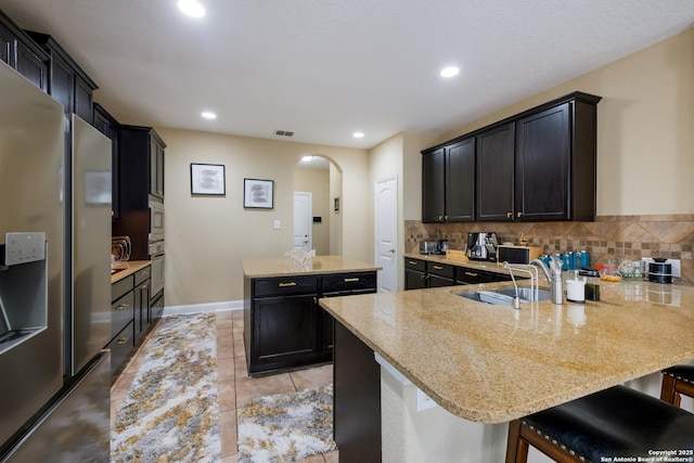 12422 Caprock Crk, San Antonio, TX 78254 - kitchen with a center island, arched walkways, backsplash, and stainless steel appliances