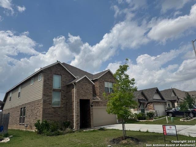 view of front of home featuring brick siding, a front lawn, an attached garage, and driveway