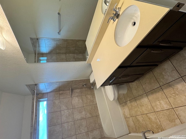 bathroom with tile patterned flooring, a sink, and a tile shower