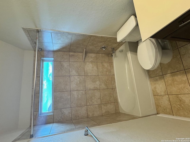 full bathroom with tile patterned flooring, toilet, and tiled shower