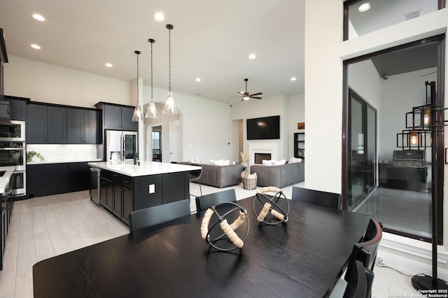 dining room featuring recessed lighting, light wood-style flooring, ceiling fan, and a fireplace