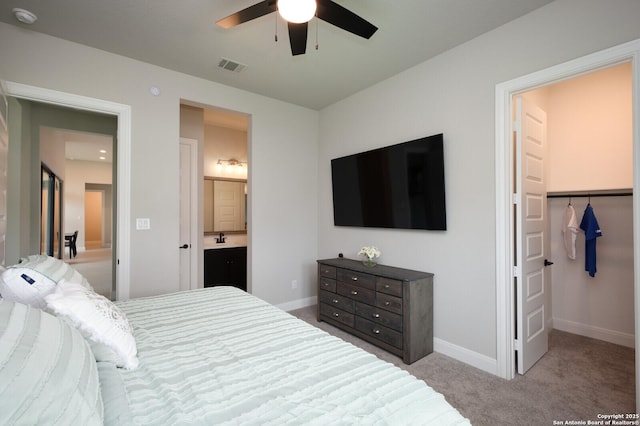 carpeted bedroom with visible vents, baseboards, ensuite bathroom, ceiling fan, and a spacious closet