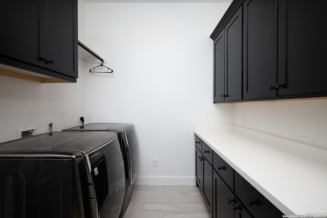 laundry room featuring baseboards, cabinet space, and washer and clothes dryer