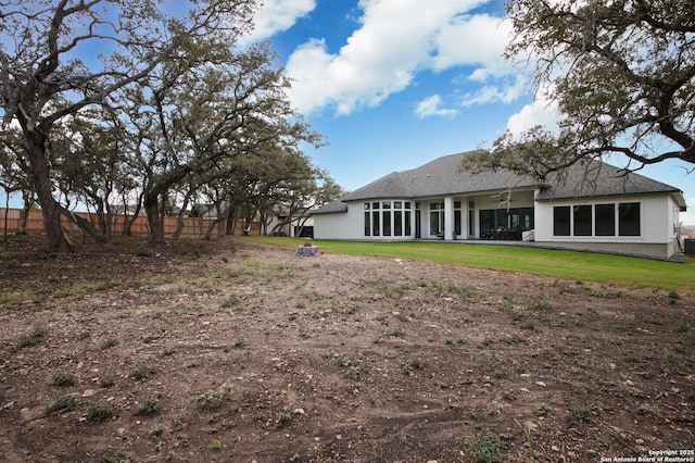 back of property with a lawn, ceiling fan, and fence