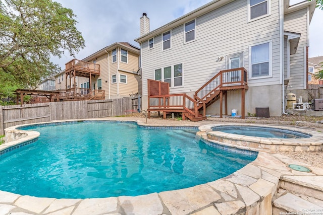 view of swimming pool with a fenced backyard, a pool with connected hot tub, a deck, and cooling unit