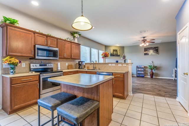 kitchen featuring tasteful backsplash, a sink, light countertops, a peninsula, and stainless steel appliances