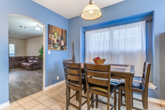 dining space with arched walkways, baseboards, visible vents, and light tile patterned floors