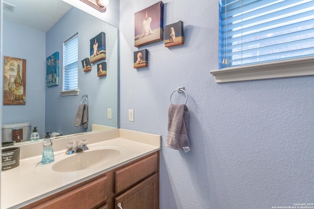 bathroom featuring visible vents, toilet, and vanity