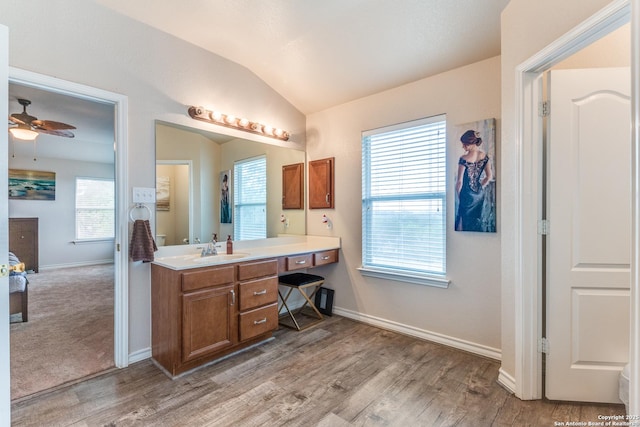 bathroom featuring ceiling fan, vaulted ceiling, wood finished floors, vanity, and baseboards
