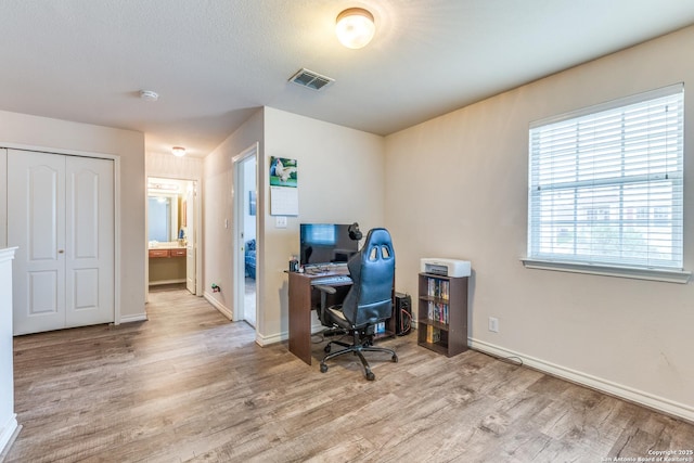 office featuring baseboards, light wood-type flooring, and visible vents