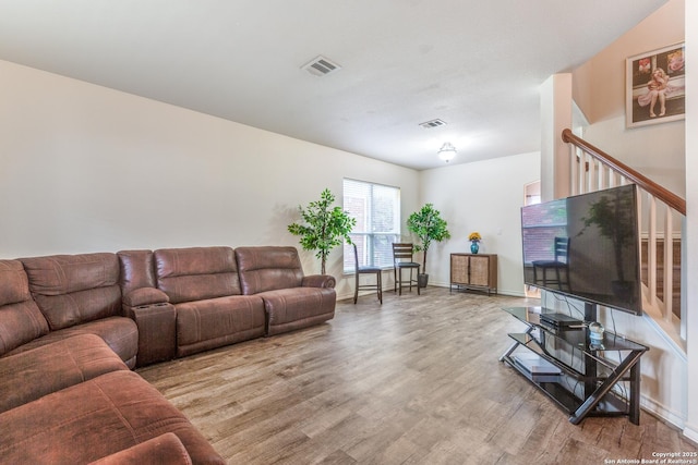living area with baseboards, visible vents, and wood finished floors