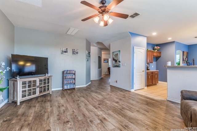 living room with light wood-type flooring, a ceiling fan, baseboards, and visible vents
