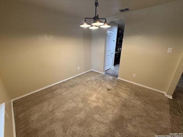 carpeted empty room with arched walkways, baseboards, and visible vents