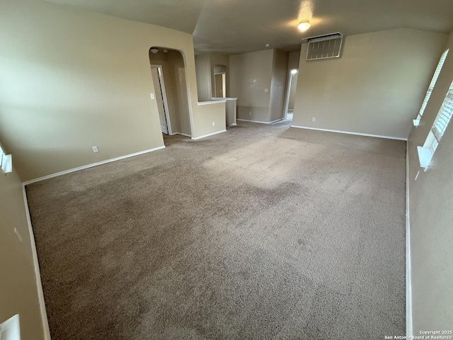 carpeted empty room with baseboards, arched walkways, and visible vents