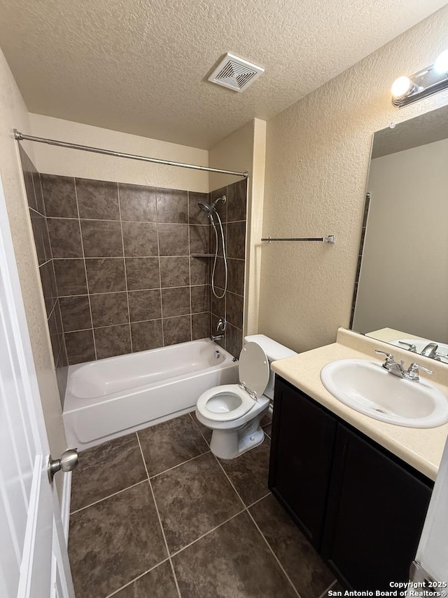 bathroom featuring tile patterned flooring, a textured wall, a textured ceiling, and visible vents