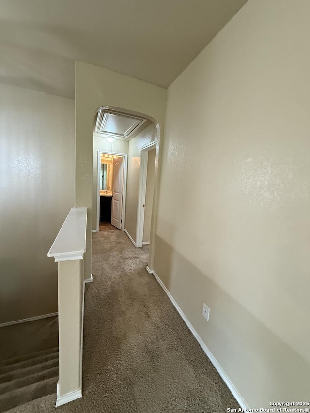 hallway featuring baseboards, carpet, attic access, and an upstairs landing