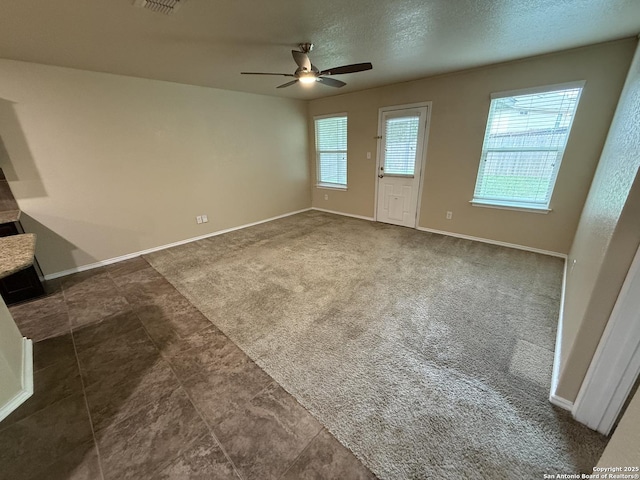 interior space featuring baseboards, ceiling fan, a textured ceiling, and visible vents