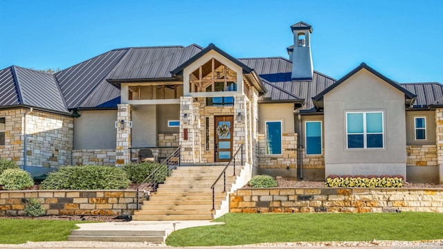 view of front of property with stucco siding, stone siding, and metal roof