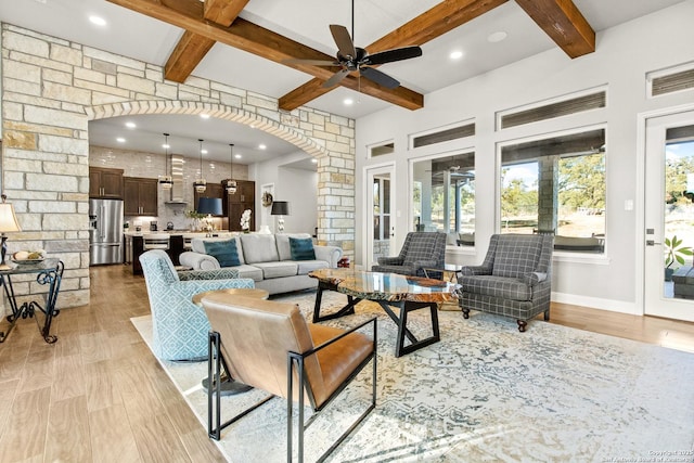 living room with ceiling fan, arched walkways, beamed ceiling, recessed lighting, and light wood-style flooring