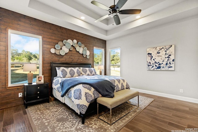 bedroom with baseboards, recessed lighting, wood finished floors, and a tray ceiling
