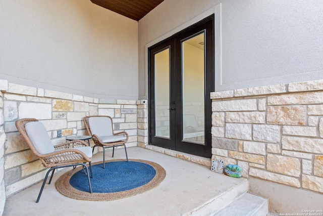 view of exterior entry featuring french doors, stucco siding, and stone siding