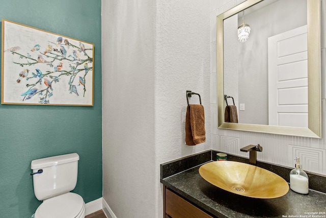 bathroom featuring vanity, a textured wall, and toilet